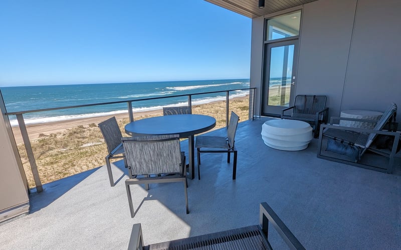 Oceanfront deck with dining table, lounge chairs, and hot tub overlooking beach and Atlantic Ocean