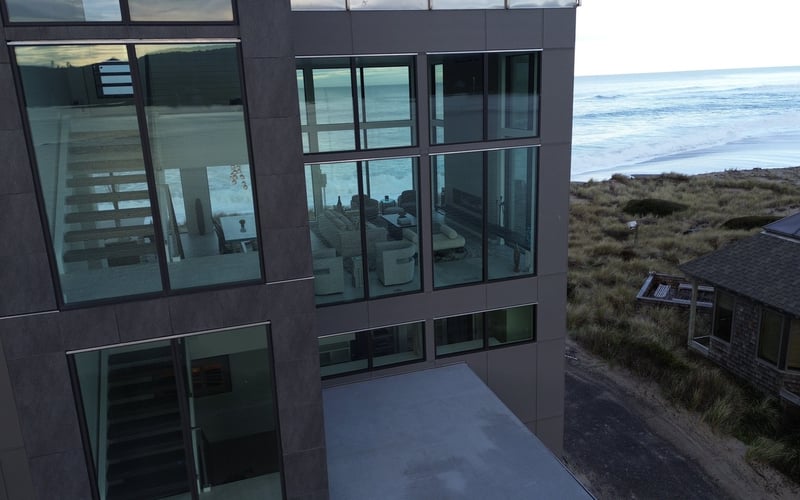Modern dark-clad beachfront house with large windows overlooking ocean and dunes